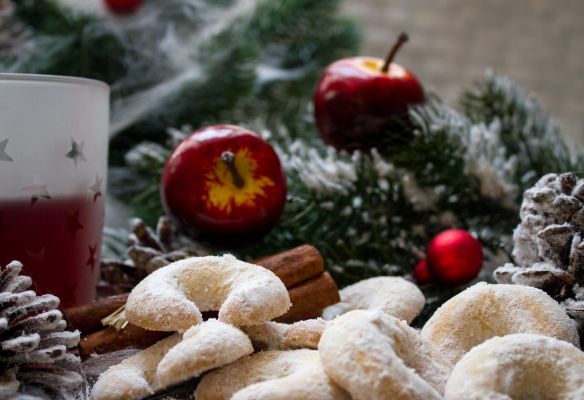 There is a glass of mulled wine and cookies on the table.