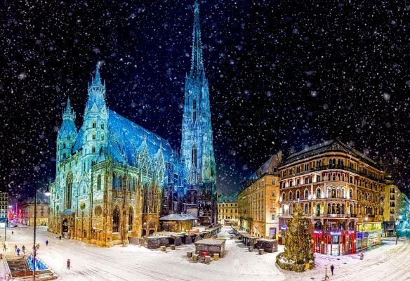 A large building with a christmas tree in front of it is surrounded by snow