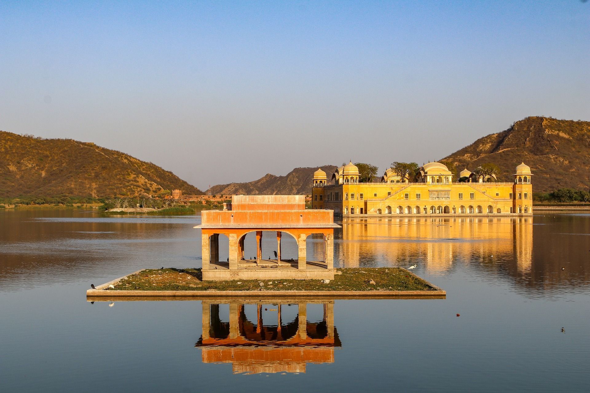 A large building is sitting on top of a small island in the middle of a lake.