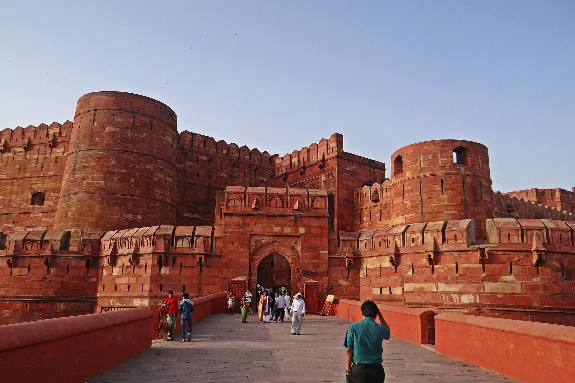 A group of people are standing in front of a large red brick building.