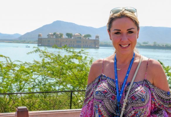 Claire Sweeney is standing in front of a lake with a castle in the background in India