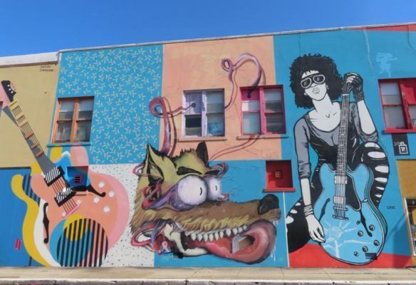 a mural on the side of a building shows a woman playing a guitar and a wolf in  Clarksdale, Mississippi