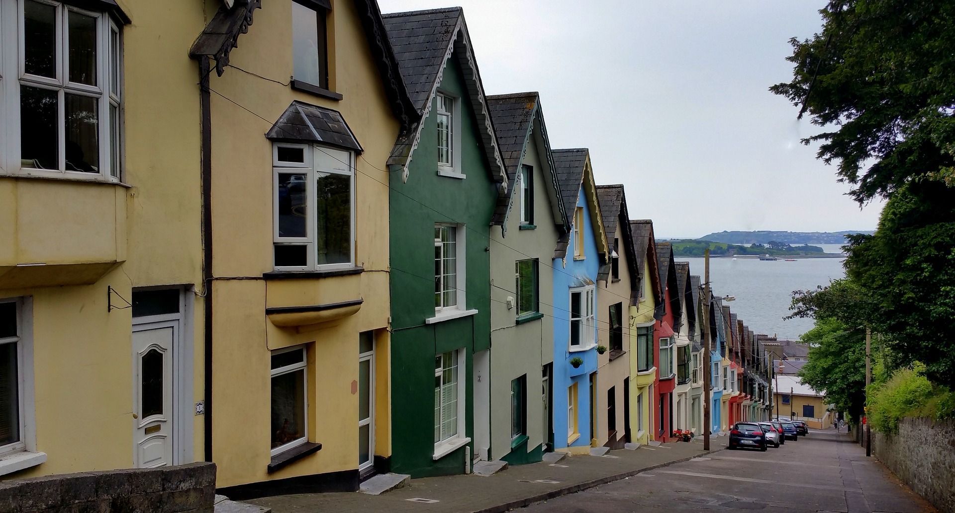 A row of colorful houses on a hillside next to a body of water.