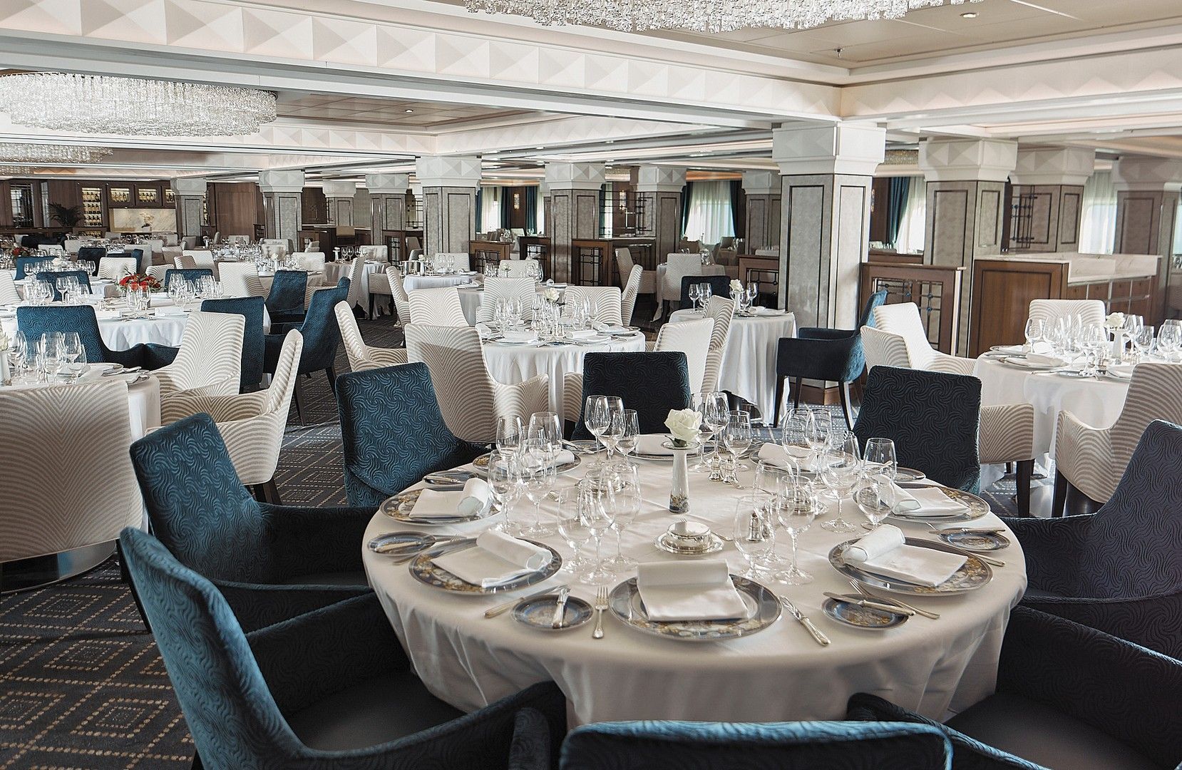 A large dining room filled with tables and chairs onboard Seven Seas Voyager cruise ship