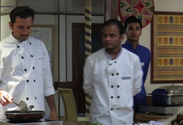 A man in a chef 's uniform is cooking in a frying pan