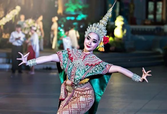 A woman in a traditional Asian costume is dancing on a stage.