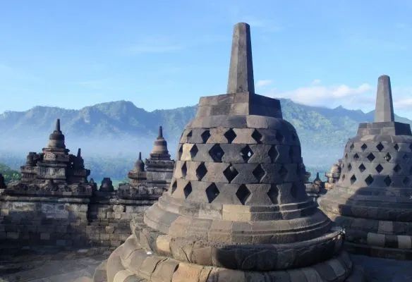 A group of stone buildings with mountains in the background in Indonesia