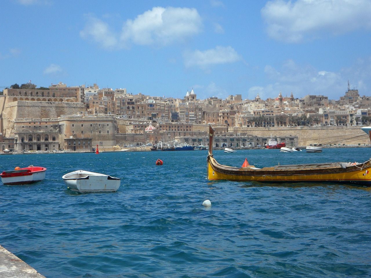 A yellow boat is in the middle of a body of water in Valletta, Malta
