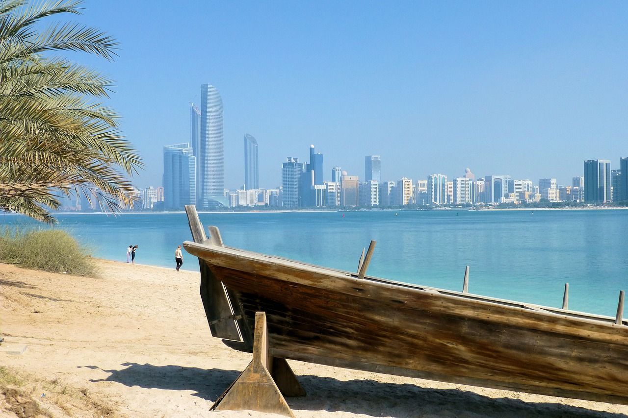 A boat is sitting on the beach with dubai  city in the background.