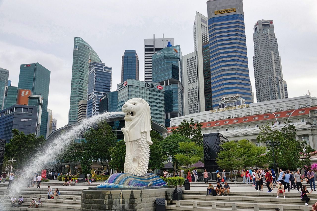 A statue of a fish is spraying water in front of a city skyline.