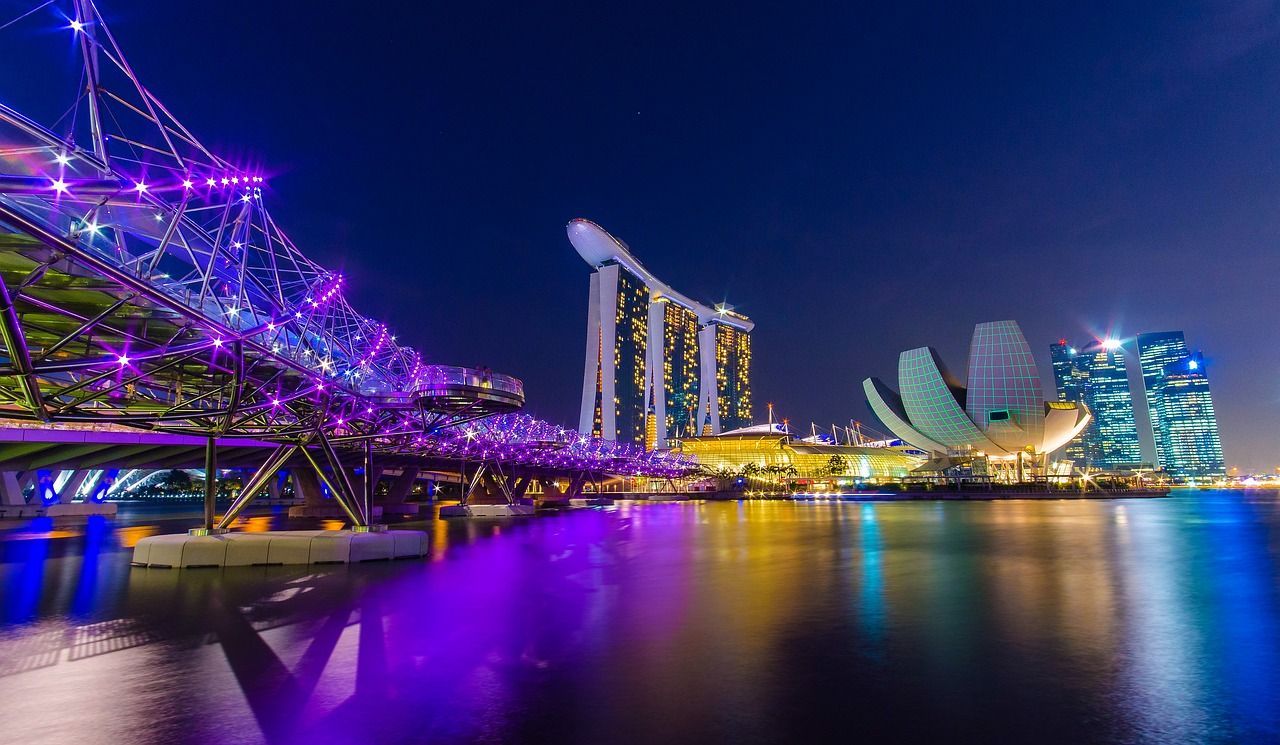 A bridge over a body of water with a city in the background at night.