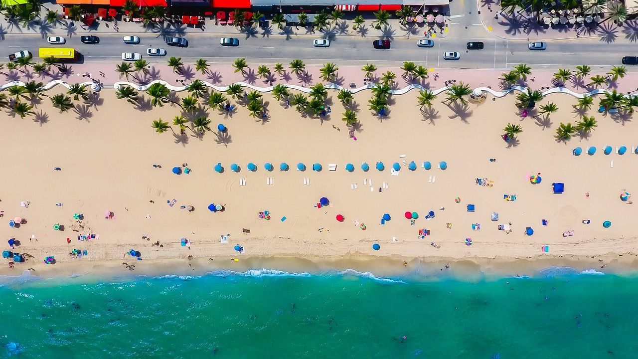 An aerial view of a beach filled with people and umbrellas.