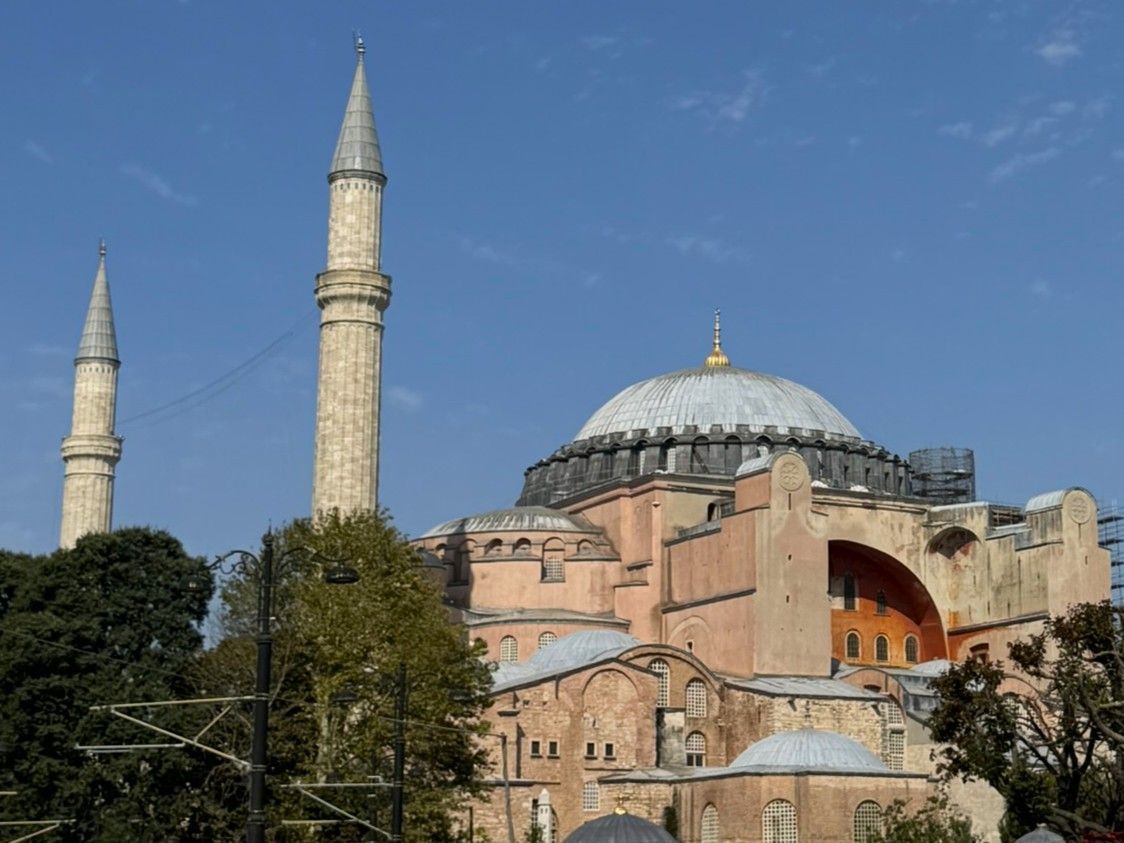 Hagia Sophia in Istanbul, Turkey. Pink-toned building with large dome, tall minarets against a blue sky.