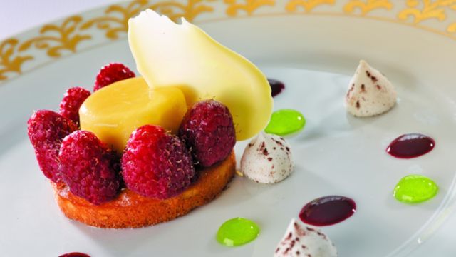 a white plate topped with a dessert with raspberries and whipped cream Culinary Masters Cruise on Oceania
