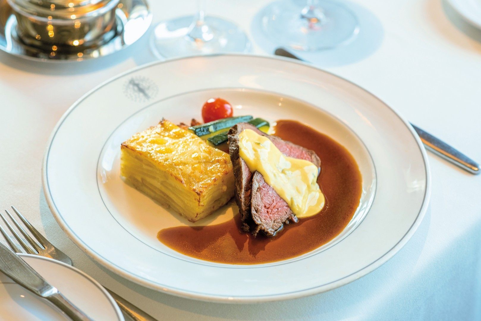 A white plate topped with a steak and mashed potatoes on a table.