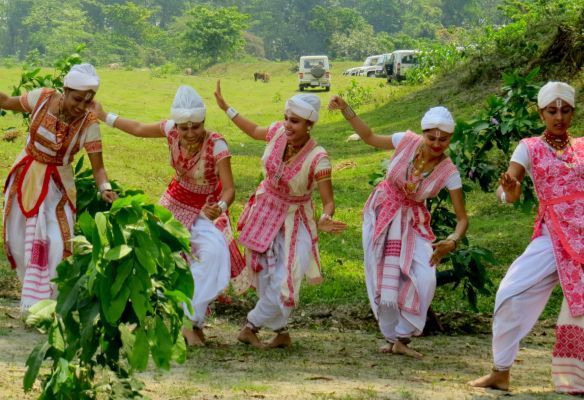 A group of people in India are dancing in a field next to the Brahmaputra River in Assam
