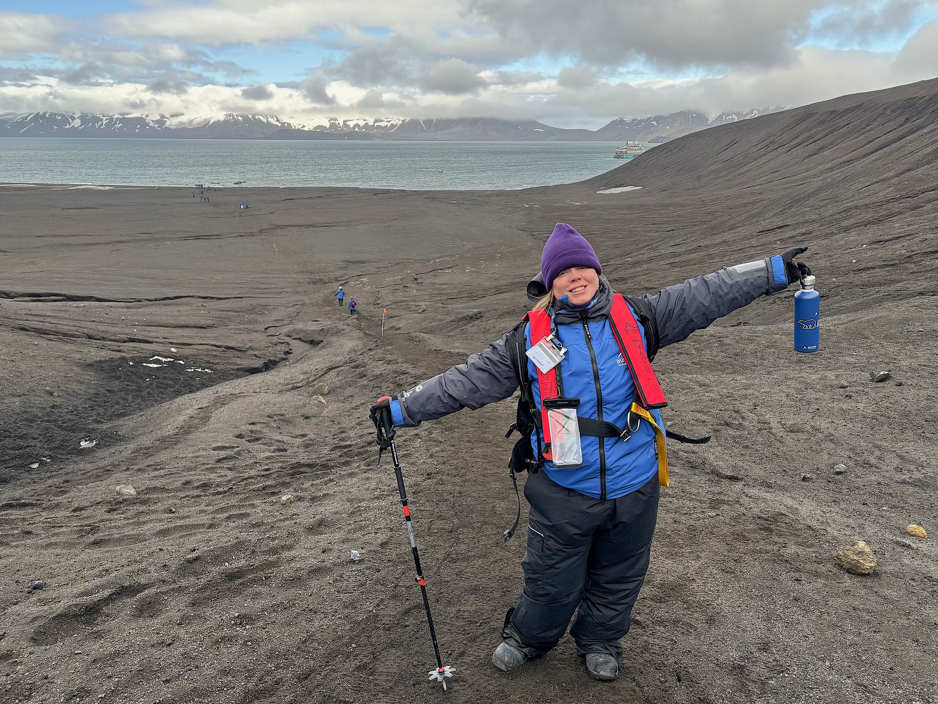 A woman is standing on a beach with her arms outstretched.