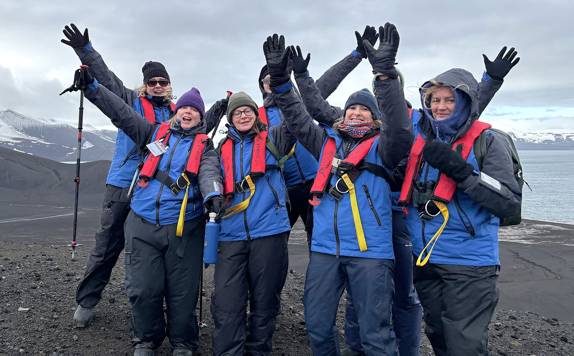 A group of people are posing for a picture with their arms in the air.