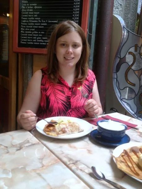 A girl is sitting at a table with plates of food