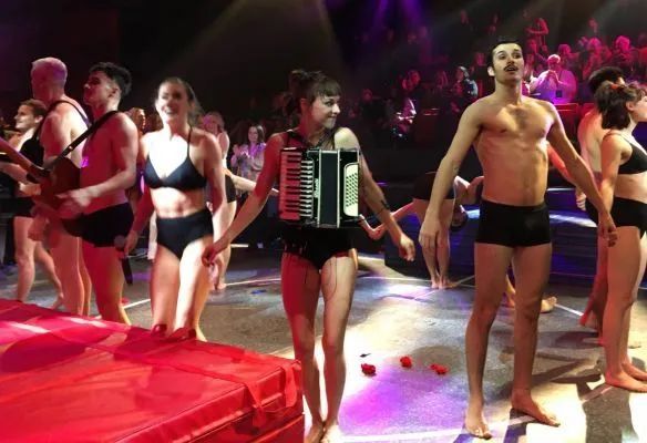 A group of people are dancing on a stage with a woman holding an accordion.