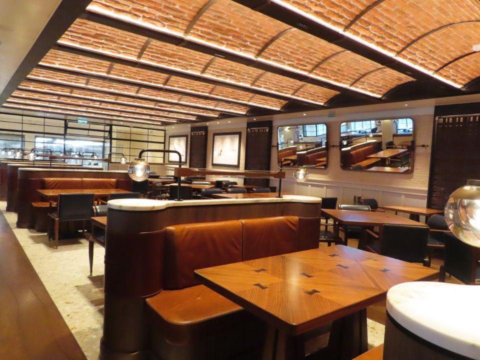 A restaurant with tables and benches and a brick ceiling