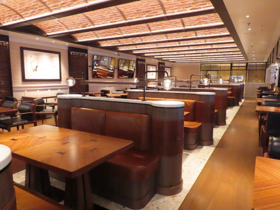 A restaurant with tables and benches and a brick ceiling