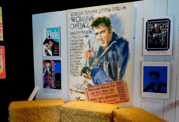 a poster of elvis presley is hanging on a wall next to hay bales at the Elvis Presley Exhibition at Graceland