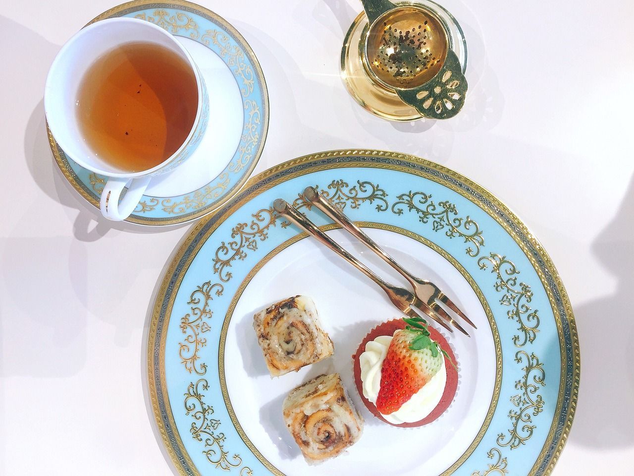 A plate with a strawberry on it next to a cup of tea on a Regent Epicurean Explorer Tour