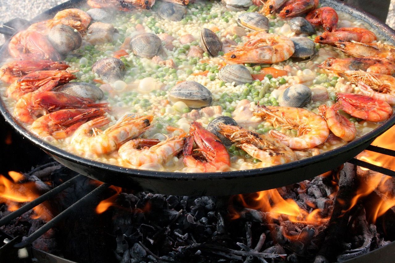 A paella is being cooked on a grill over a fire on a Regent Epicurean Explorer Tour