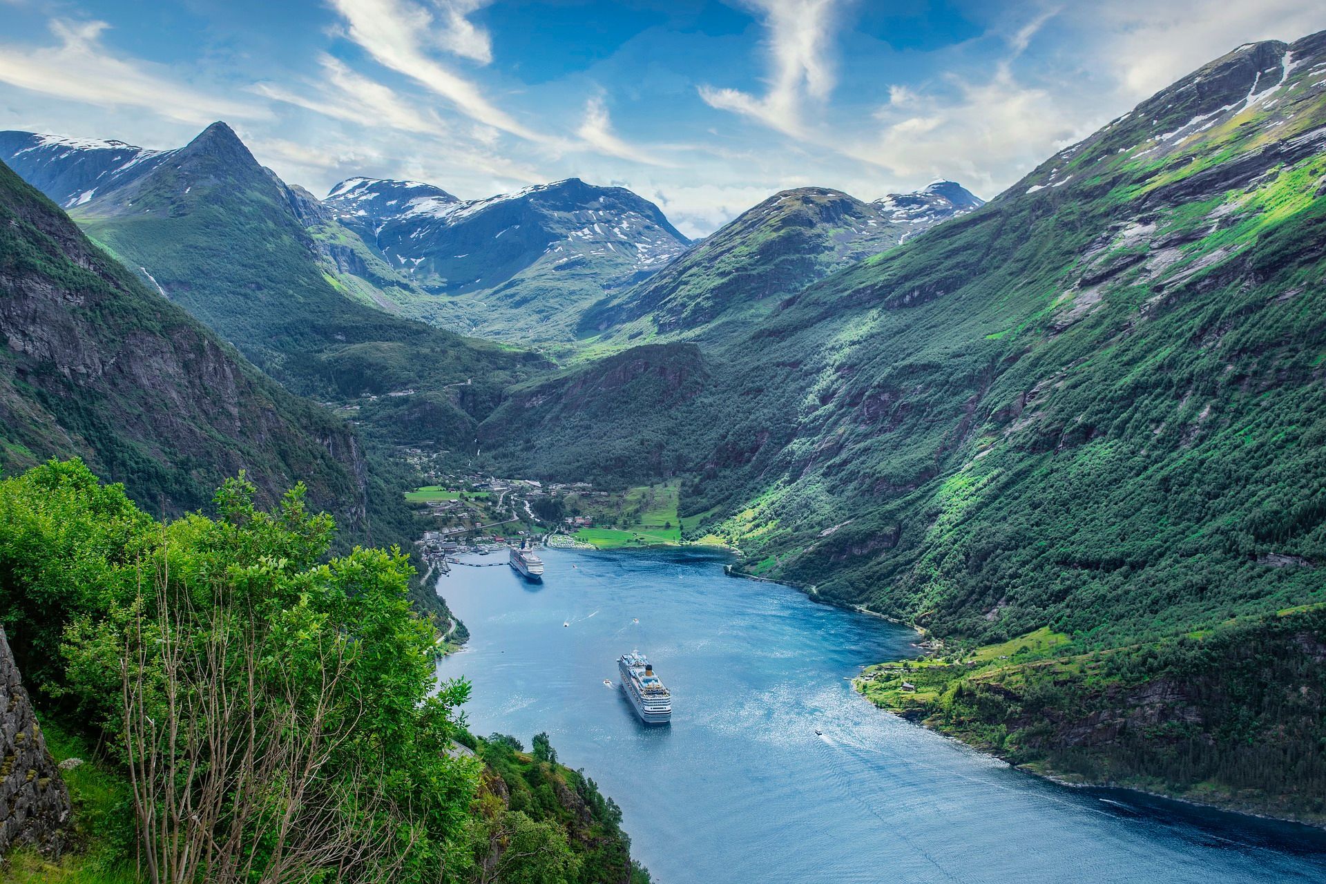 A boat is floating on a lake surrounded by mountains in a fjord in Norway