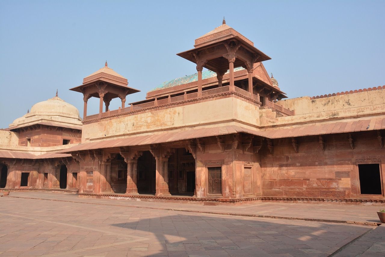 A large red brick building with a lot of arches and a blue sky in the background.