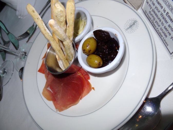 A plate of food with olives and bread sticks on a table