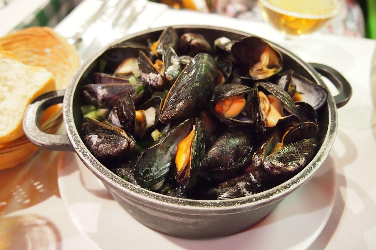 A bowl of mussels is on a white plate on a table Oceania Cruises Culinary Discovery Tour