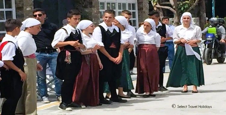 A group of people in traditional costume are standing on a street.