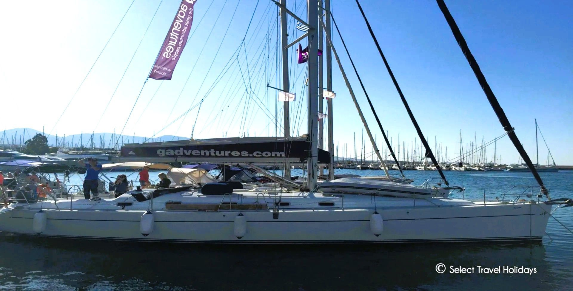 g adventures sailboat is docked in a harbor with people on it.