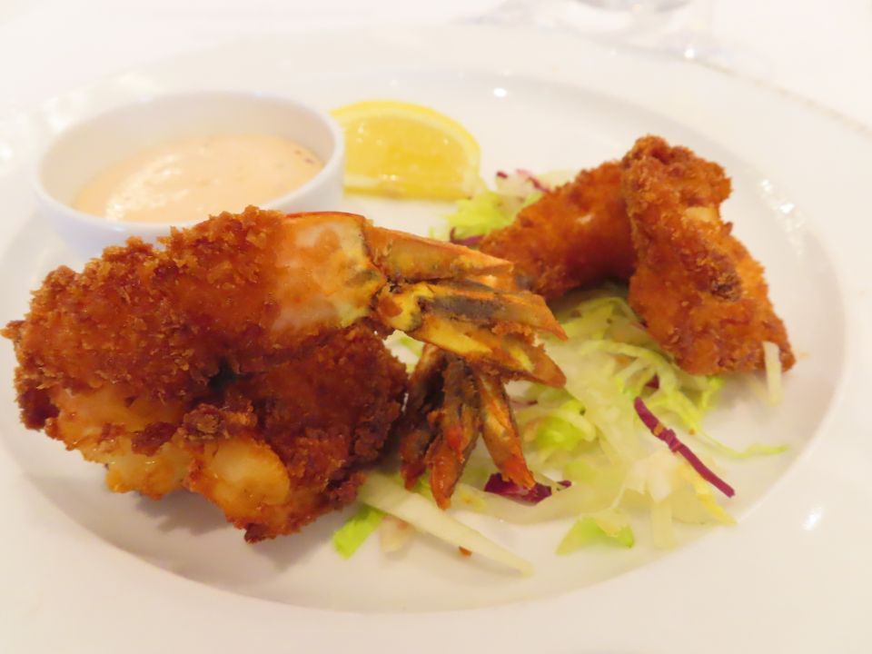 A white plate topped with fried shrimp , lettuce and sauce.