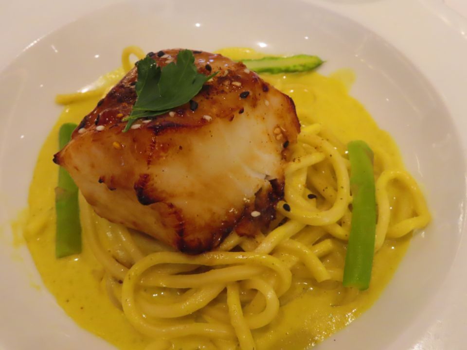 A close up of a plate of food with noodles and meat on a table.