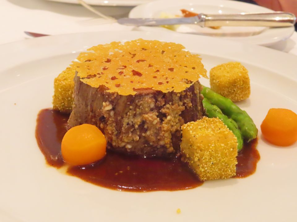 A white plate topped with a piece of meat and vegetables