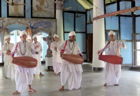 A group of men are playing drums in a room performing the Gayan Bayan Dance