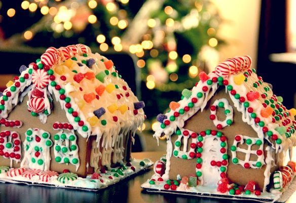 Two gingerbread houses are sitting on a table in front of a christmas tree.