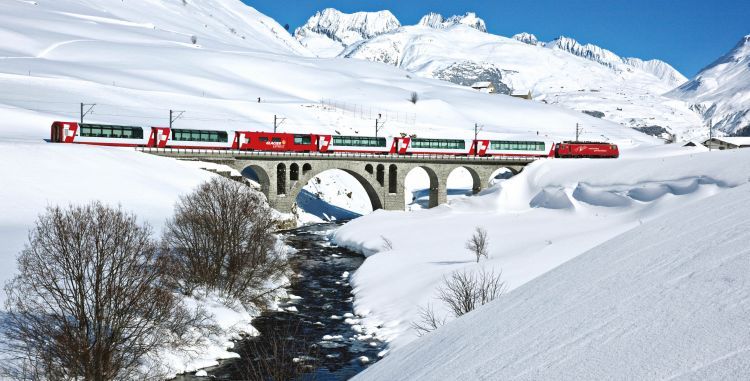 A train is going over a bridge in the snow.