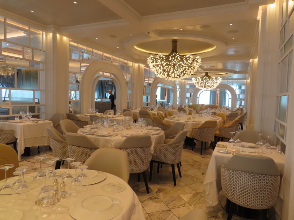 A large dining room filled with tables and chairs and a chandelier.