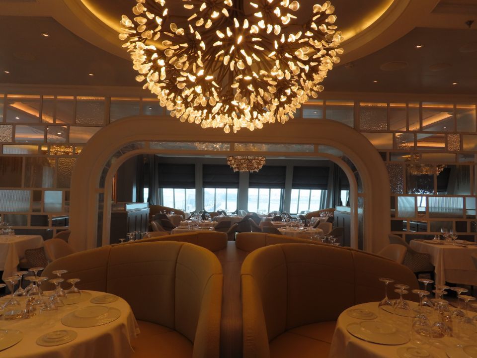 A restaurant with tables and chairs and a large chandelier