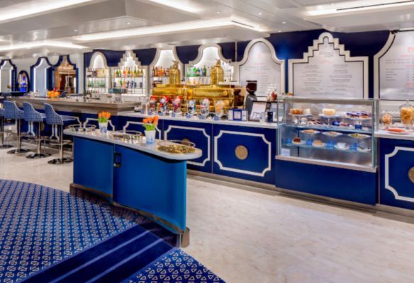 a restaurant with blue and white furniture and a display case filled with food onboard Koningsdam