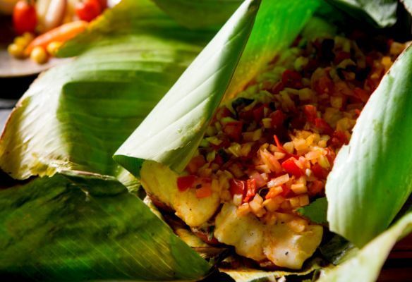 A close up of food wrapped in banana leaves on a table