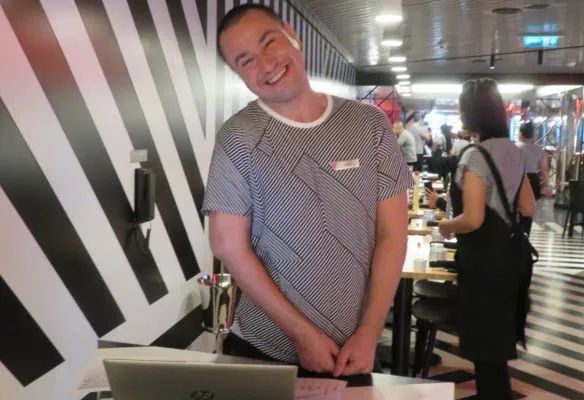 A man standing in front of a laptop in a restaurant