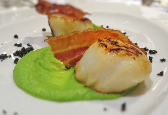 A close up of a plate of food with scallops and bacon on Hebridean Princess