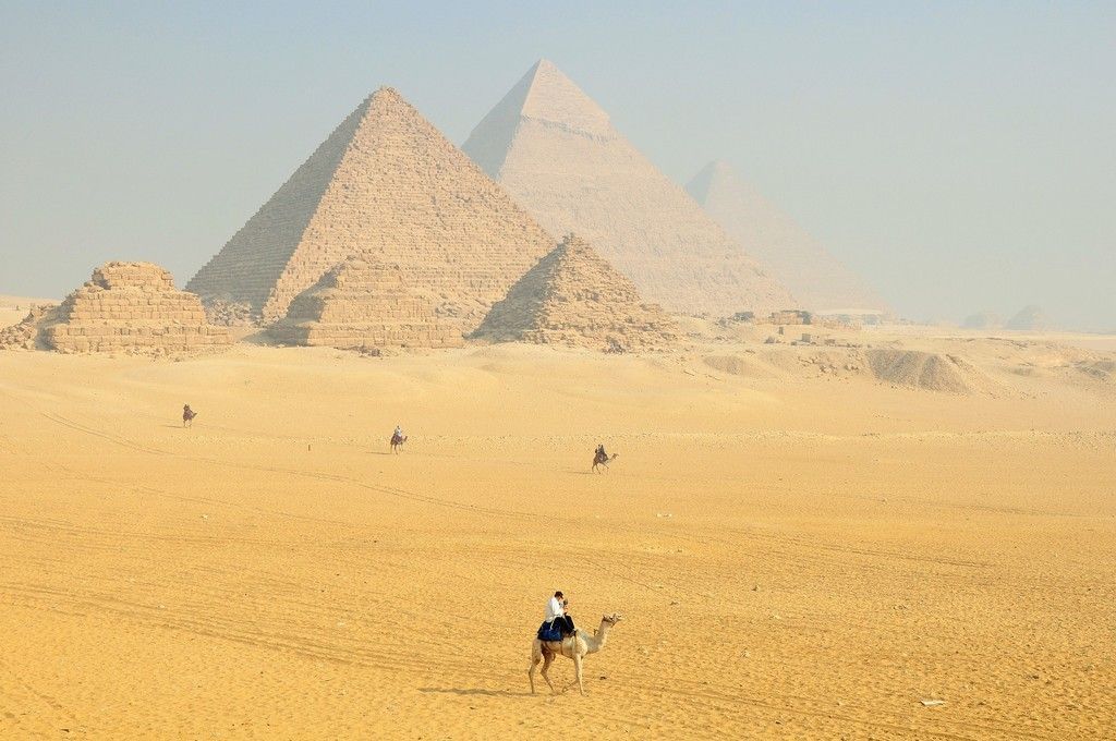 a man is riding a camel in front of the pyramids in the desert 