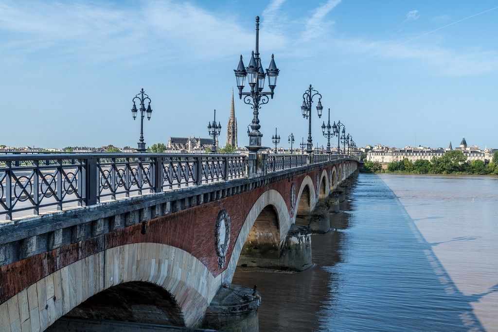 a bridge over a river with Bordeaux city in the background .