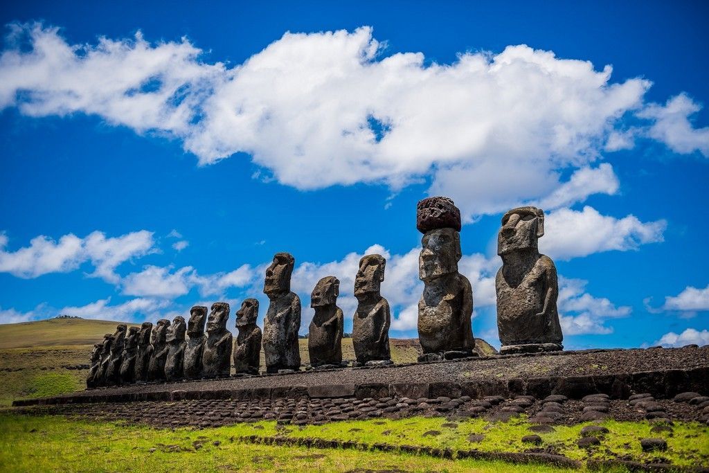 a group of statues standing next to each other in a field on Easter Island